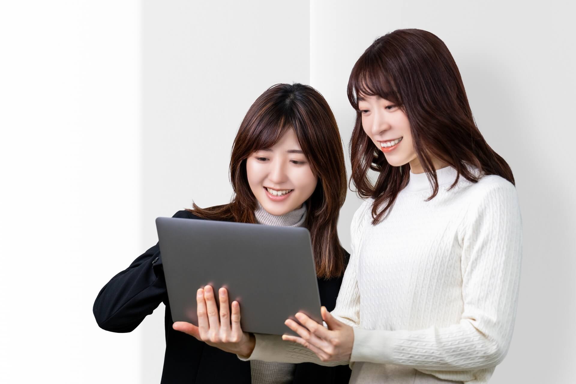 パソコンの前で笑っている2人の女性の画像