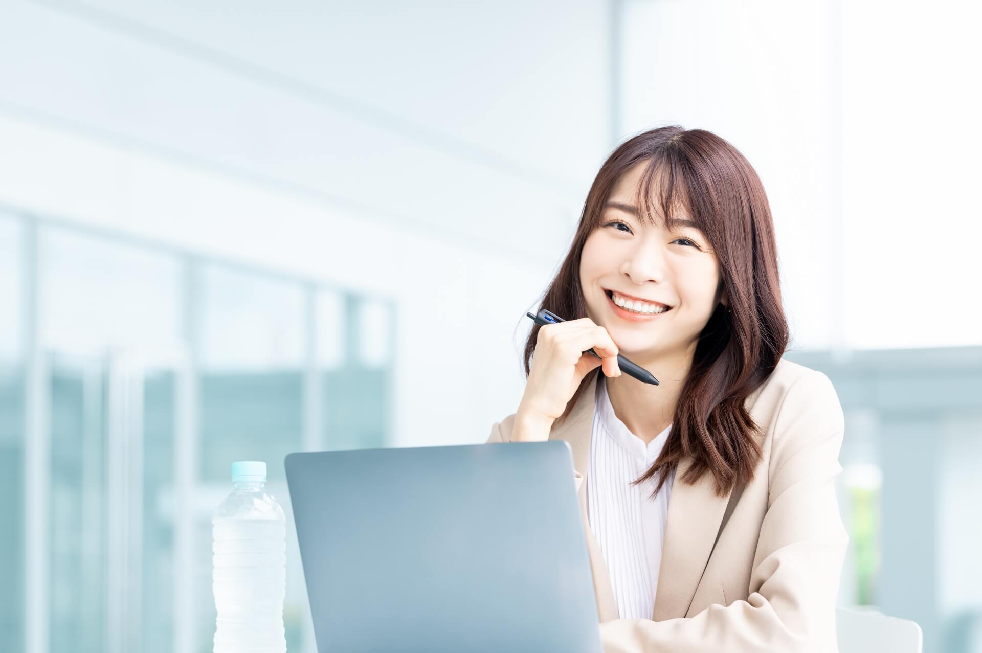 ノートパソコンの前で笑顔を浮かべている女性の画像